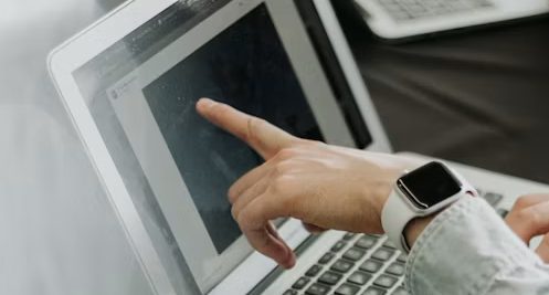 Dłoń wskazuje ofertę na ekranie laptopa