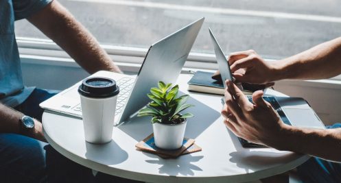 Dwie osoby pracują razem przy laptopach przy jednym stoliku